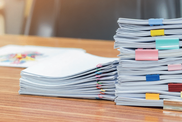 A stack of exam papers or coursework divided by coloured tabs.